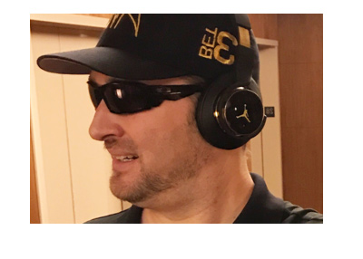 Phil Hellmuth caught walking down the hall with an Aria hat and dark headphones.