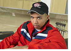 promotional photo of poker player phil ivey - relaxing in a red track suit - on the couch - with a full tilt hat